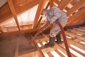 Technician installing blown-in cellulose insulation in attic