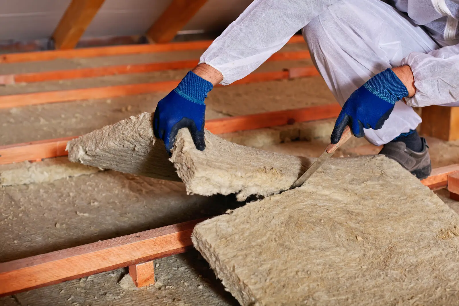 Old mineral wool batts being lifted out of attic for removal