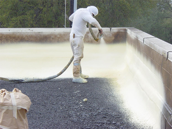 Contractor applying spray foam insulation to commercial flat roof